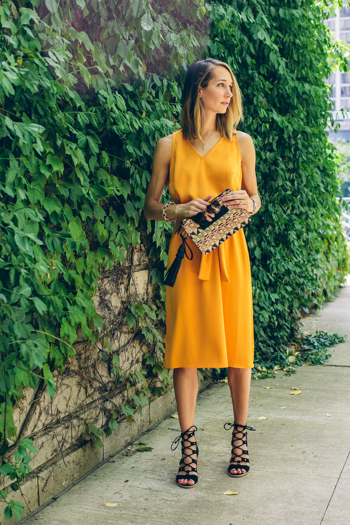yellow tie dress with straw tassel clutch and lace up heels