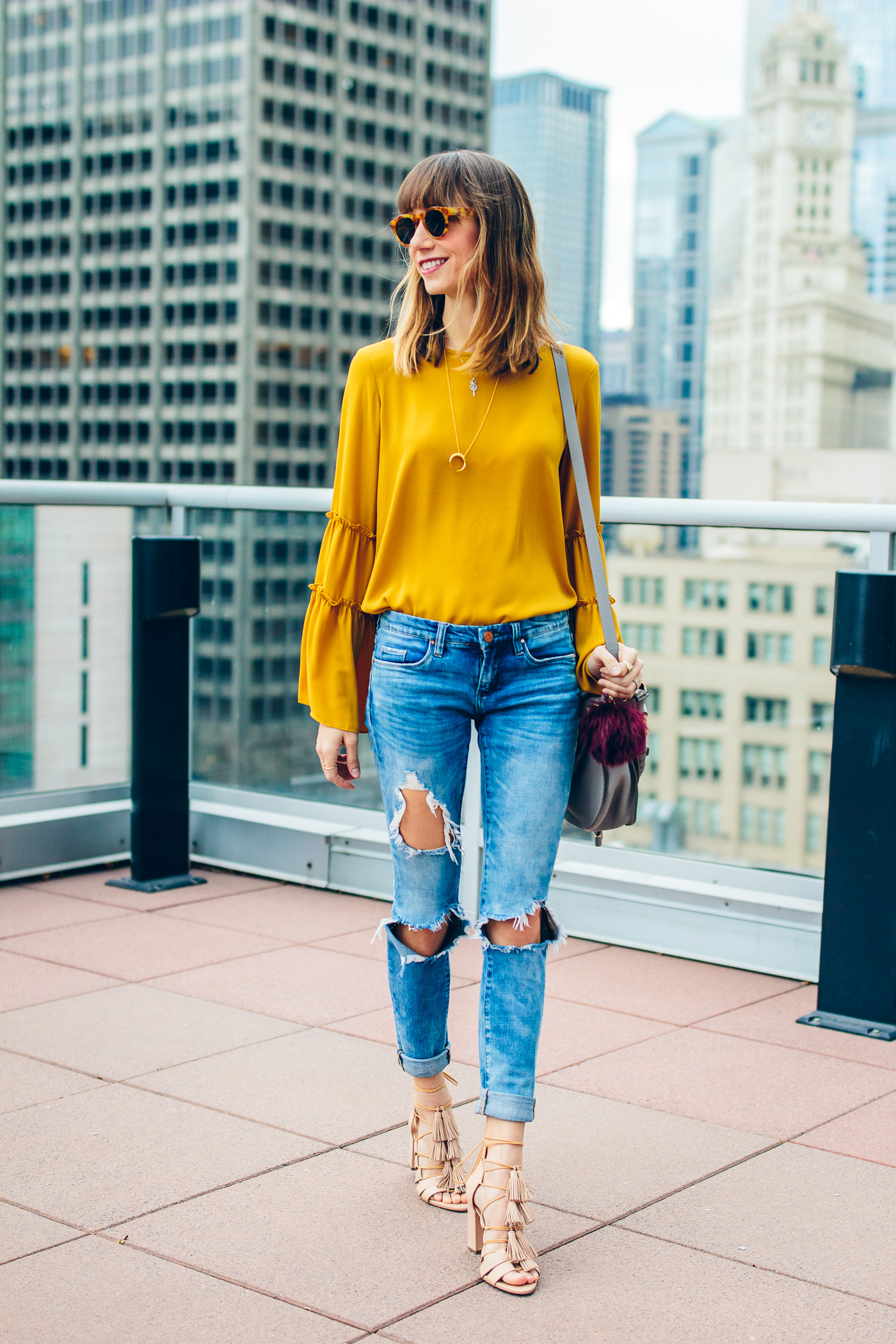 Chicago Fashion blogger, Blair Staky wearing ripped jeans, bell sleeve shirt and tassel heels