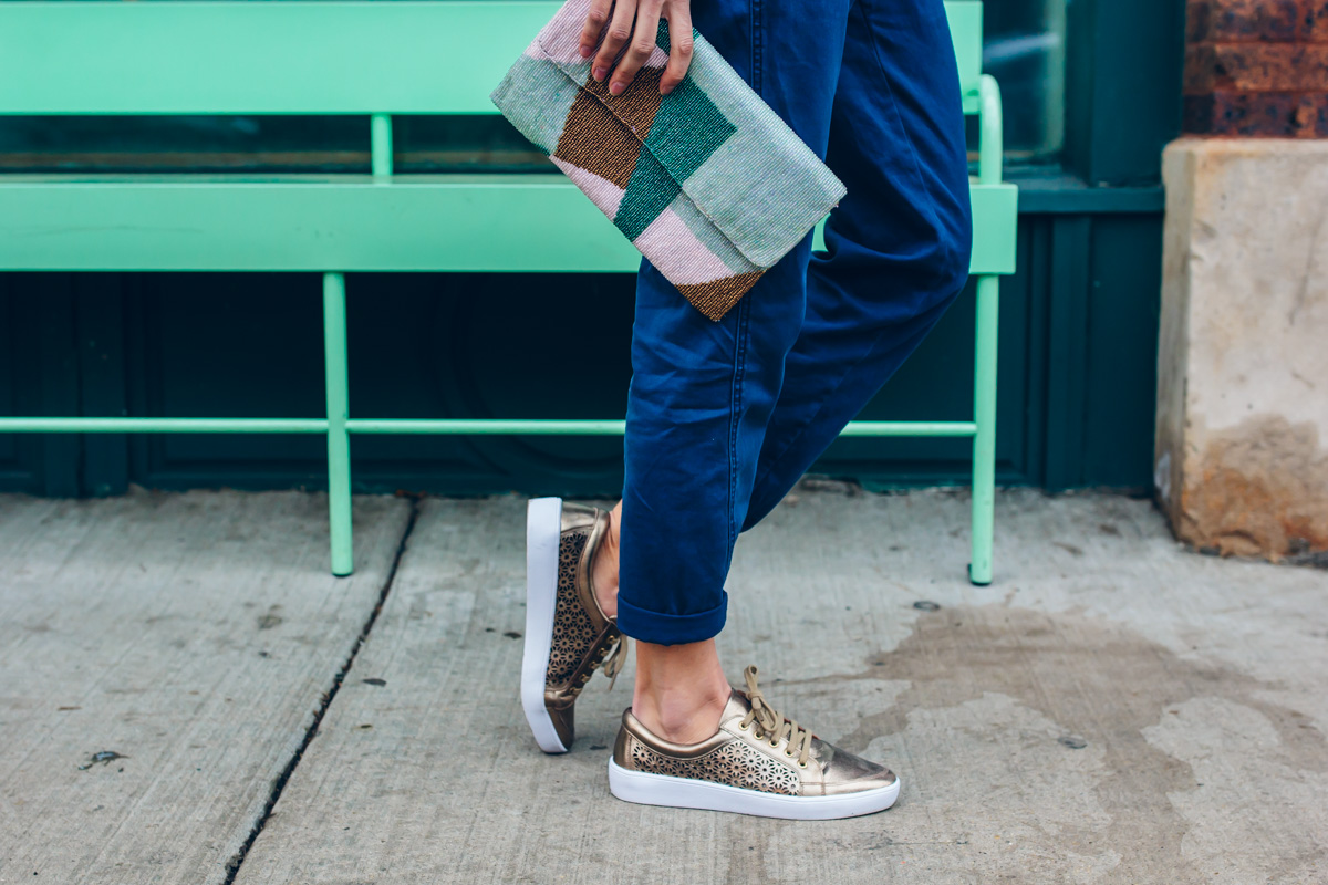 gold sneakers and a beaded clutch