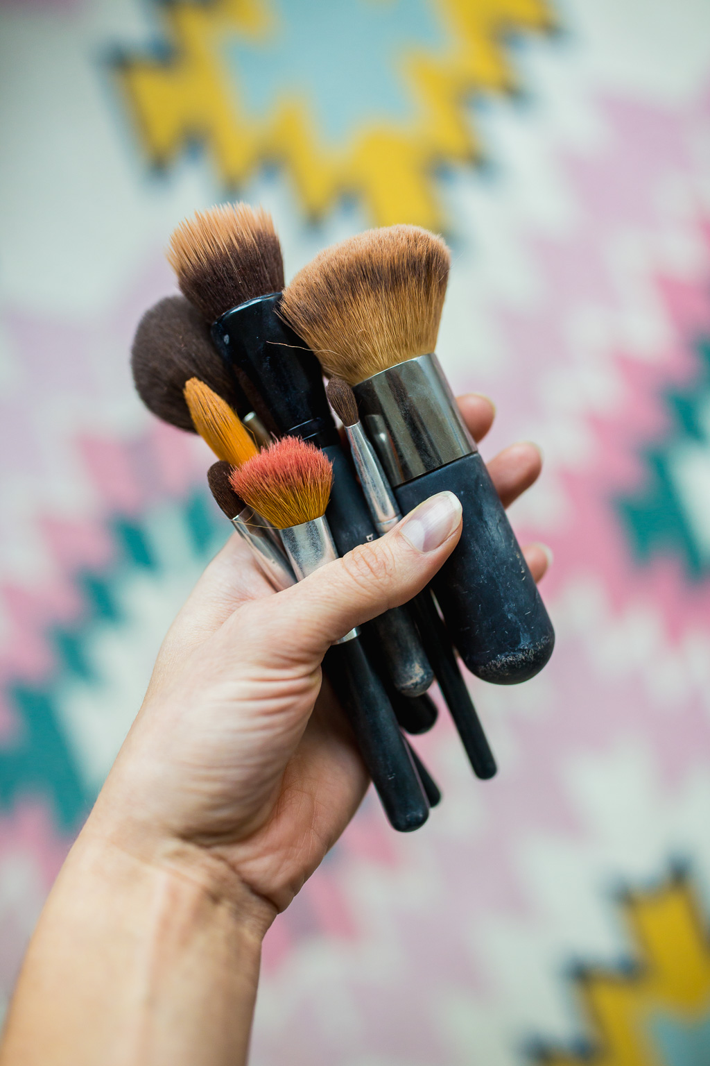 woman holding dirty makeup brushes
