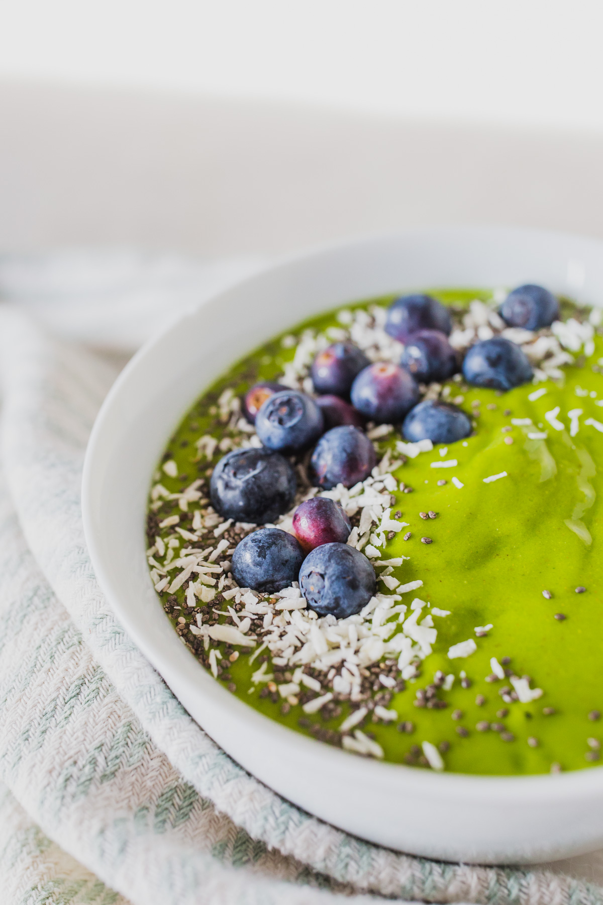 Looking for new ways to eat greens? This healthy green smoothie bowl is one of the easiest ways to get in your daily greens like spinach or kale and fruit! Healthy eating for beginners doesn't have to be difficult, and this green smoothie recipe makes it taste delicious! This easy smoothie bowl recipes is a natural energy booster and immunity booster! Click through for my spinach smoothie recipe that tastes like a tropical drink. #greensmoothie #smoothiebowlrecipes