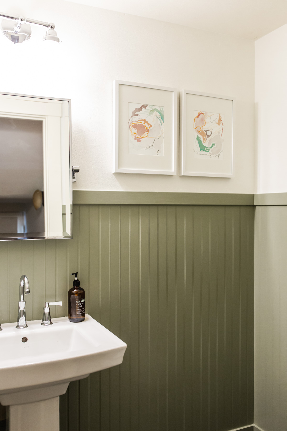Beadboard to a Bathroom with paintings, white sink, and mirror